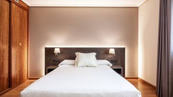 Habitación de hotel con cama grande, armario de madera y dos lámparas de noche.