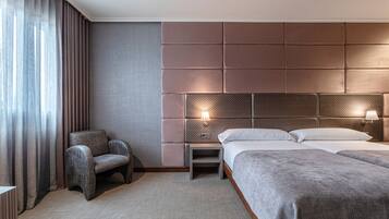 Habitación de hotel con una cama grande, una silla, una mesita de noche y una lámpara de pared.
