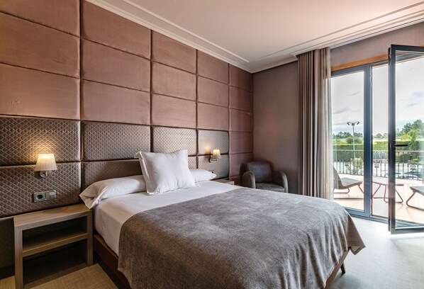 A hotel room with a large bed, a nightstand, a wall-mounted lamp, and a view of the outdoors through a sliding glass door. - Hotel Pensua Punta del Este (Carballo)
