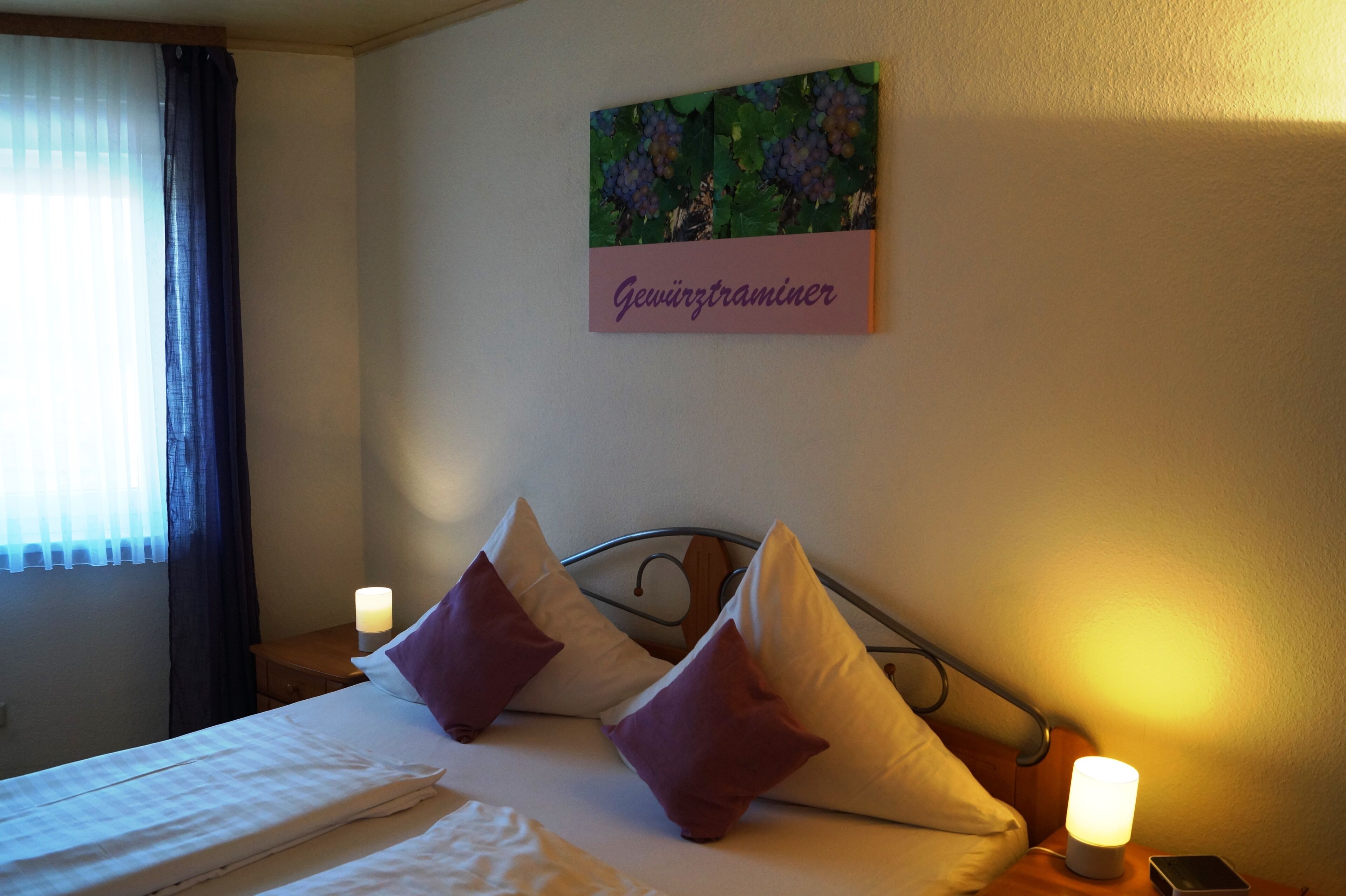 A neatly made bed with two pillows, a bedside lamp, and a wall-mounted artwork with text.