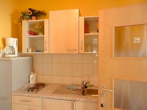 A kitchen with cabinets, a coffee maker, a sink, and a countertop. - Gästezimmer  Weingut Peter (Wachenheim an der Weinstrasse)