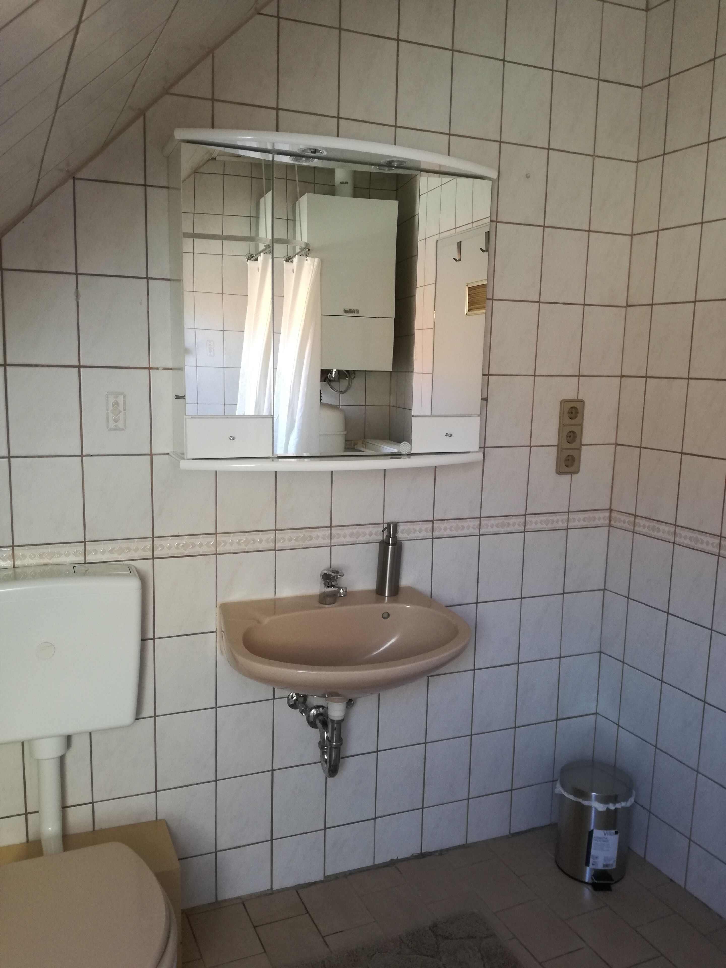 Een badkamer met een wastafel, spiegel en toilet.