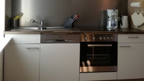 A modern kitchen with white cabinets, stainless steel appliances, and a black microwave. - Gästezimmer  Weingut Peter (Wachenheim an der Weinstrasse)