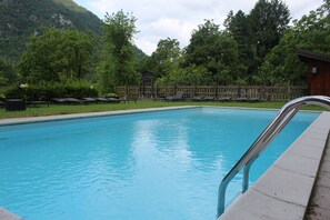 Una piscina al aire libre de temporada, sillones reclinables de piscina