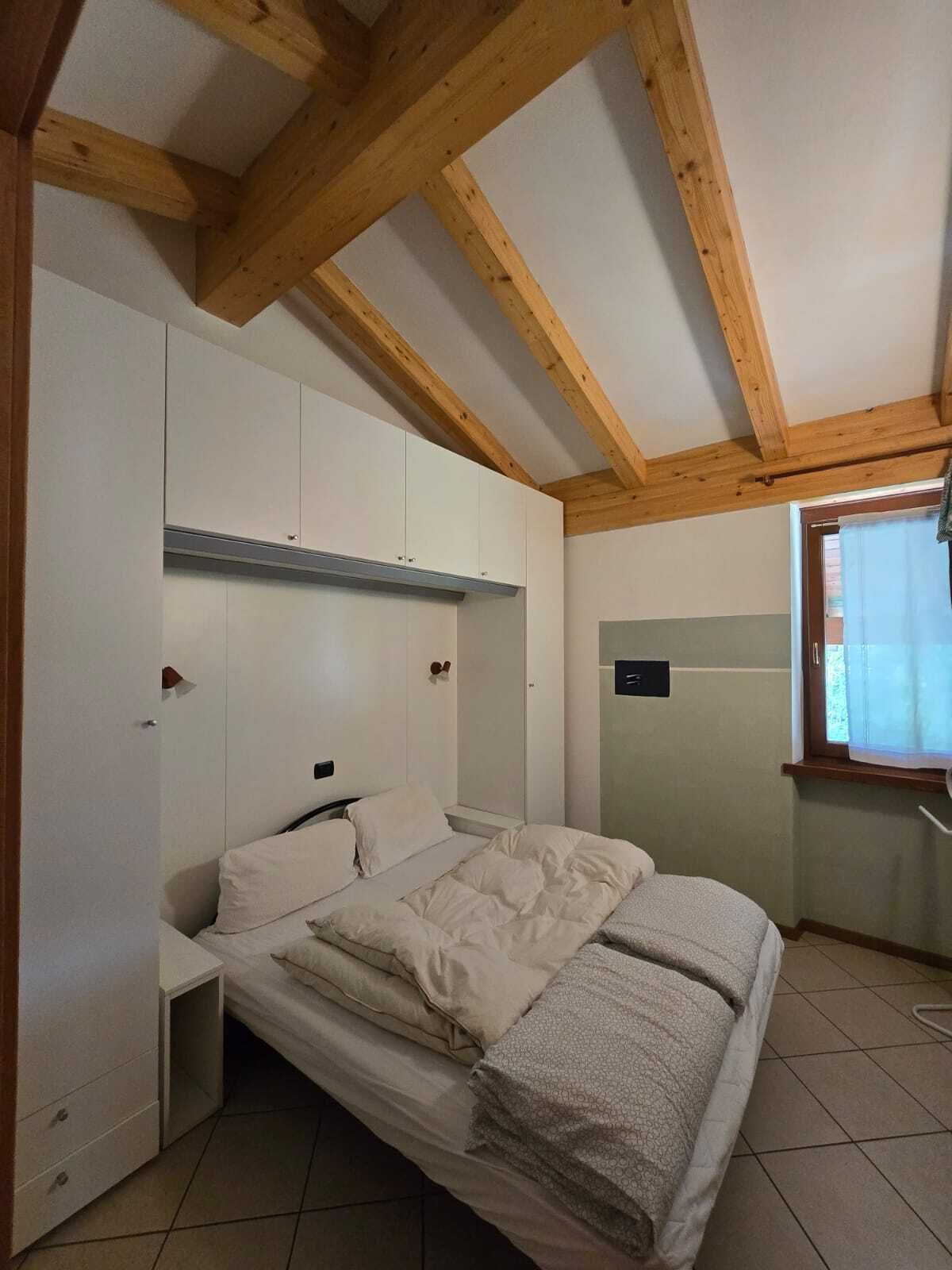 A bedroom with a bed, built-in wardrobe, and a window with curtains.