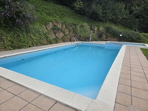Una piscina al aire libre de temporada, sillones reclinables de piscina