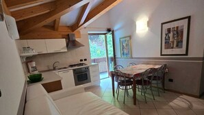 Una cocina acogedora con comedor, que presenta techo de madera, paredes blancas y suelo de baldosas.