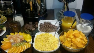 A buffet table with various food items including fruits, chips, and beverages.