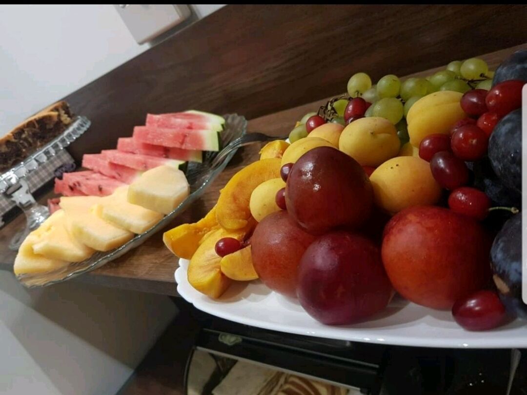 A fruit platter with watermelon, cantaloupe, peaches, grapes, and plums.