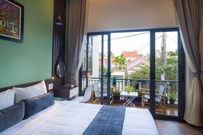 A hotel room with a large bed, a view of the balcony, and a painting on the wall.