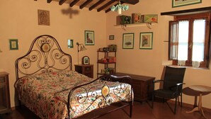 Un dormitorio con cama, una silla, un escritorio y ventana.