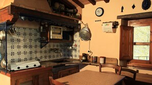 Una cocina con una mesa y sillas de madera, estufa y lavamanos.