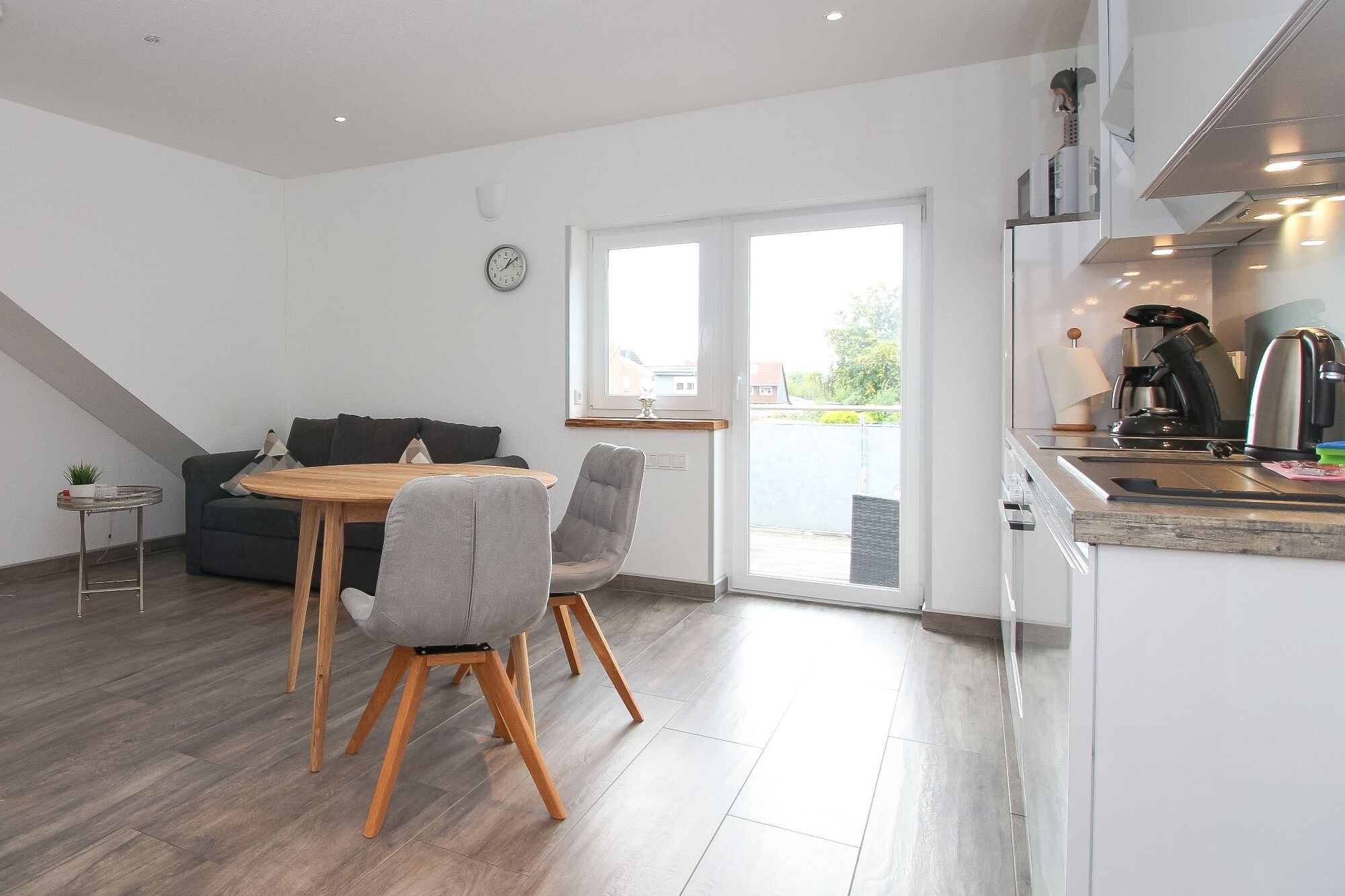 A modern kitchen with a dining area, including a table, chairs, and a sofa.