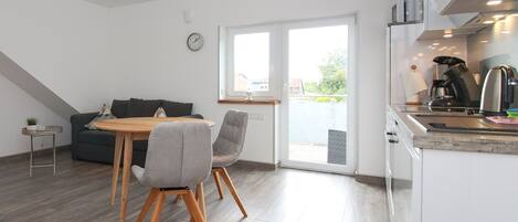 A modern kitchen with a dining area, including a table, chairs, and a sofa.