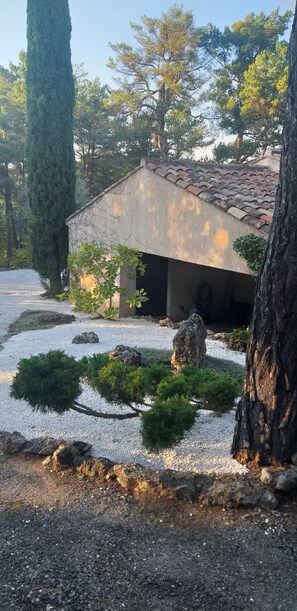 A traditional building with a tiled roof, surrounded by a gravel path and small trees.