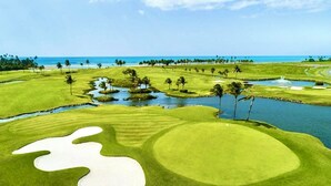 Un campo de golf con obstáculos acuáticos, bunkers de arena y vistas al océano.