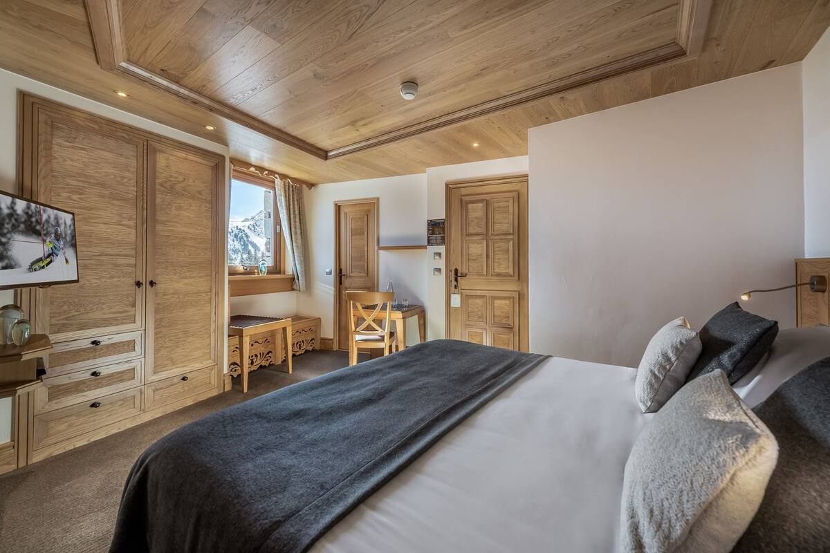Une chambre à coucher avec un grand lit, une armoire en bois, un bureau et une chaise.