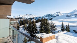 Un edificio moderno con balcón de cristal con vistas a un paisaje montañoso nevado.
