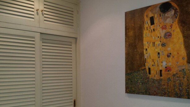A room with a closed white door and a painting of a couple embracing on the wall. - Beautiful apartment (Madrid)