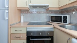 A compact kitchen with a microwave, stove, oven, and a sink. - Beautiful apartment (Madrid)