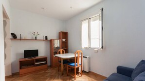 A compact living space with a television, wooden furniture, a dining table, and a sofa. - Beautiful apartment (Madrid)