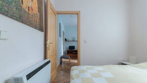 A bedroom with a bed, a radiator, a wooden door, and a small stool. - Beautiful apartment (Madrid)