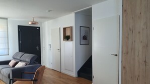 Un salon moderne avec un canapé, un fauteuil, un plancher en bois et un escalier menant à un autre niveau.