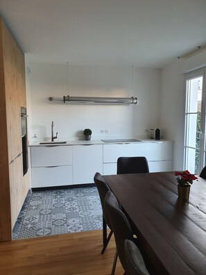 Una cocina moderna con armarios blancos, un extractor de acero inoxidable y un ventanal con vistas.