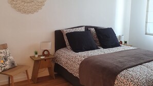 Une chambre à coucher comprenant un lit, une table de chevet en bois, une lampe de chevet et un élément décoratif mural.