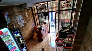 A hotel lobby with a Coca-Cola vending machine, a reception desk, and a seating area with chairs and tables.