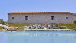 A stone building with a tiled roof, a pool, and several lounge chairs. - Residence a Badesi ID 3369 (Trinita d'Agultu e Vignola)