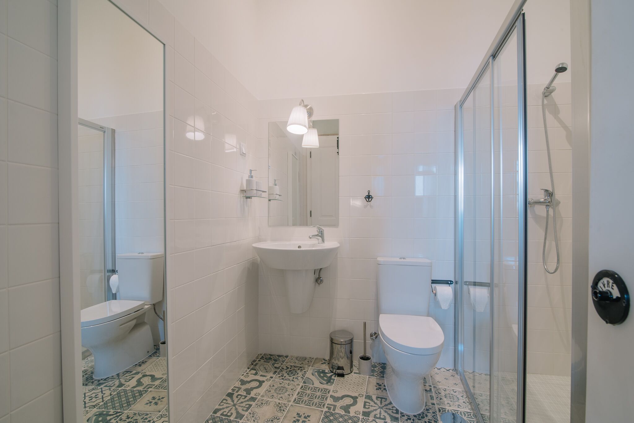 Un baño con cabina de ducha de vidrio, un lavabo blanco y un inodoro.