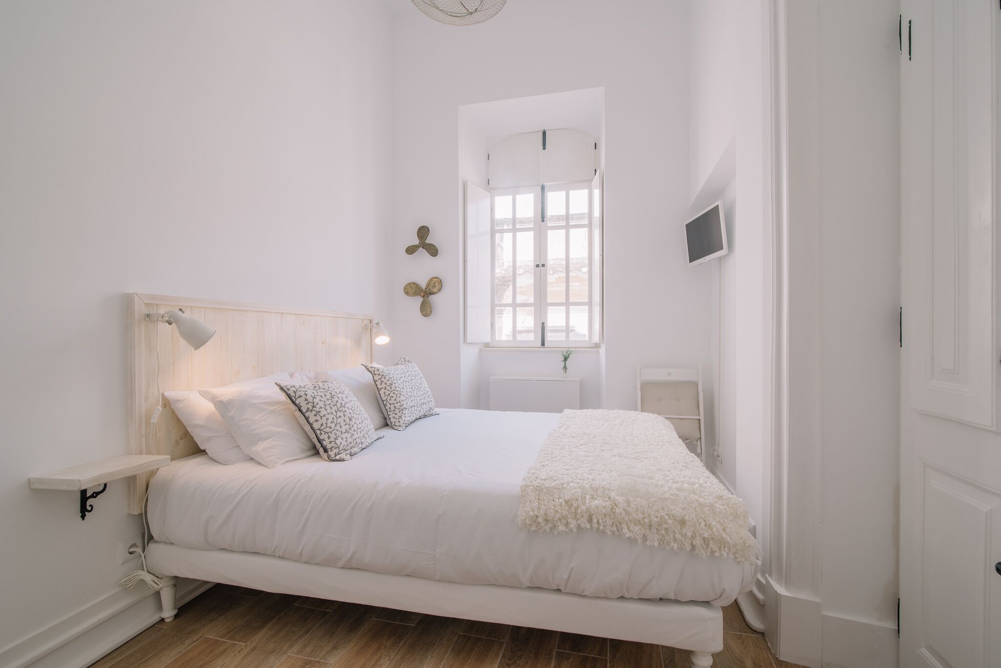 A minimalist bedroom with a bed, bedside tables, a window, and a door.