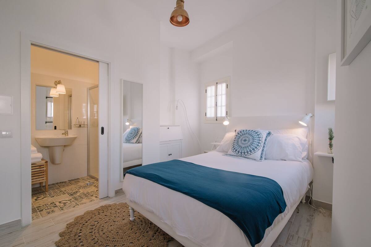 Une chambre à coucher avec un lit, une table de chevet, une lampe et une fenêtre.