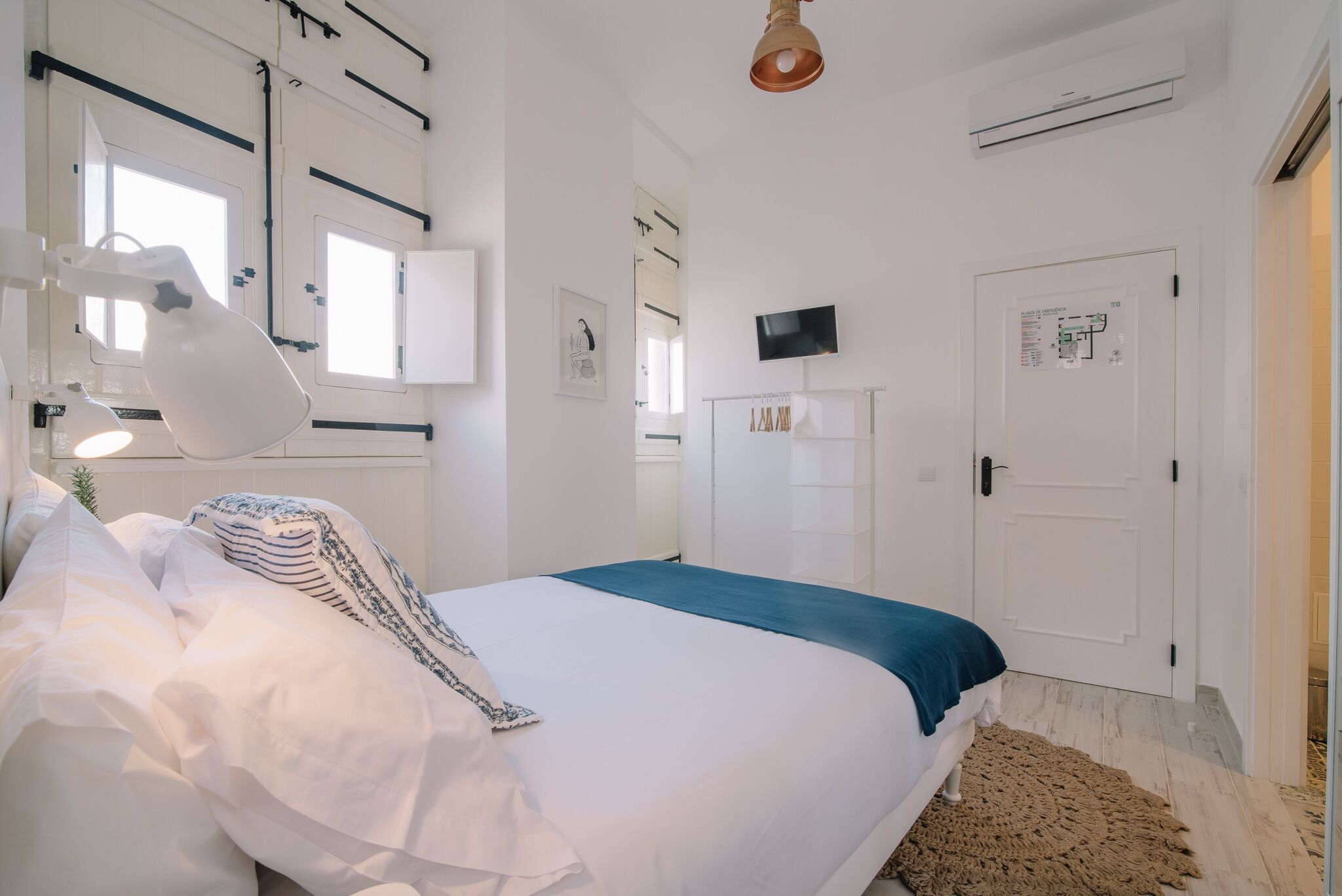 Une chambre à coucher avec un lit, une lampe de bureau, un téléviseur et une porte sur laquelle est affiché un avis.