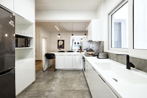 A modern kitchen with white cabinetry, a large island, and pendant lighting. - Kolonaki Square Executive Apartment (Athens)