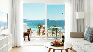 Una habitación de hotel con balcón, sofá, mesa de comedor y fruta, y televisor.