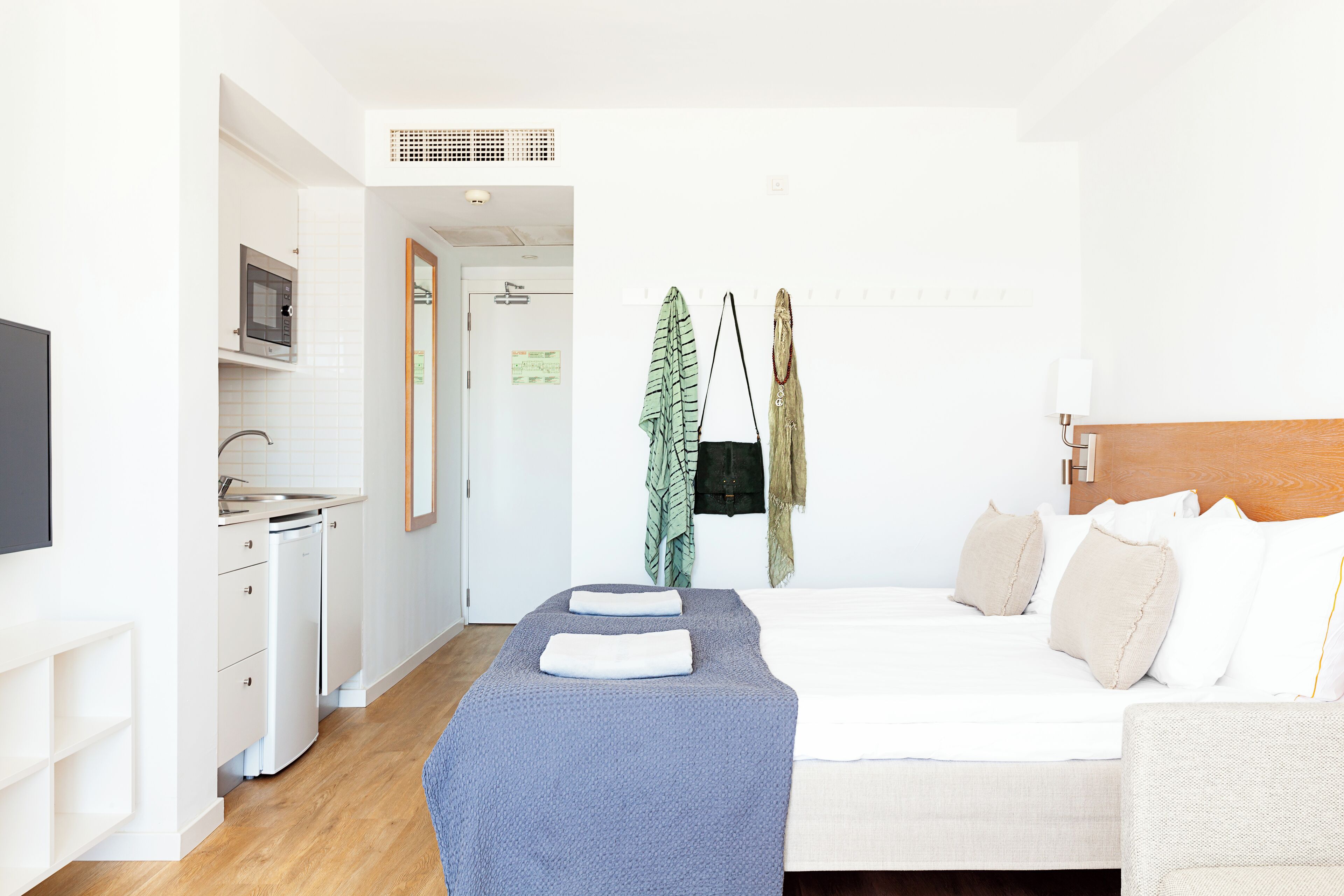 A hotel room with a bed, a bedside table, a TV, a microwave, a sink, and a wardrobe.