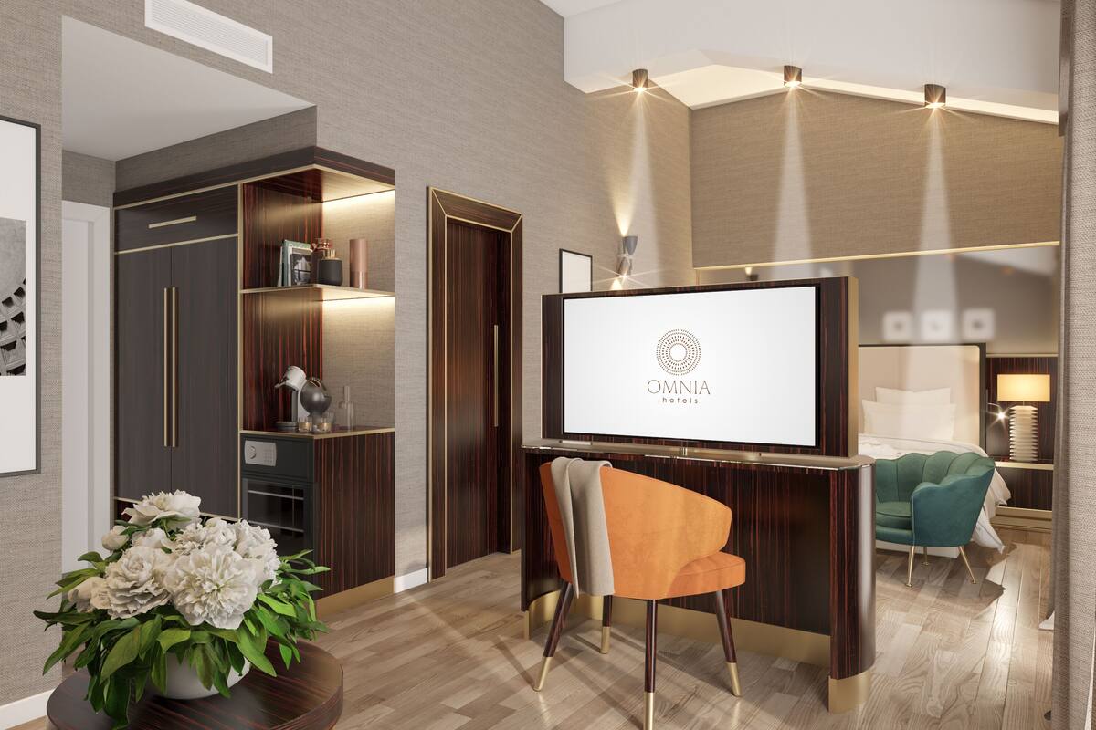 A modern hotel room with a large flat-screen TV, a comfortable seating area, and a well-organized closet.