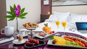 Habitación de hotel con bufé de desayuno, un ordenador portátil sobre la cama y un cuadro en la pared.