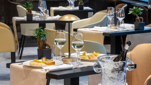 Un ambiente de restaurante con mesas dispuestas para comer, incluyendo platos de comida, copas de vino y una botella de champán en una jarra de cristal.