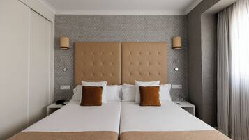 A double bed with a tufted headboard, two bedside tables with lamps, and a herringbone-patterned wall.