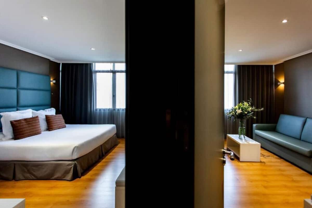 Een moderne hotelkamer met een groot bed, een bank en een tafeltje met een bloevas.