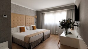 Hotelkamer met een groot bed, een bureau, een televisie en een raam met gordijnen.