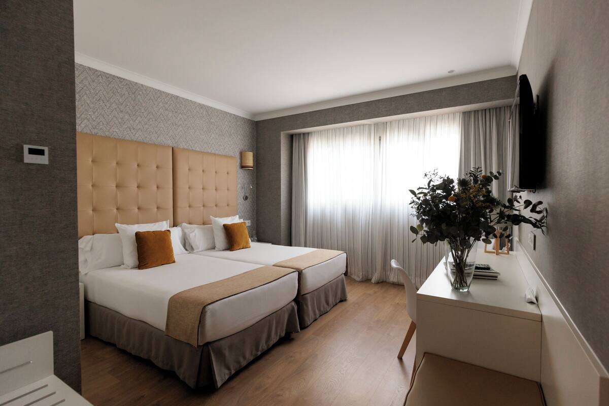 Hotelkamer met een groot bed, een bureau, een televisie en een raam met gordijnen.
