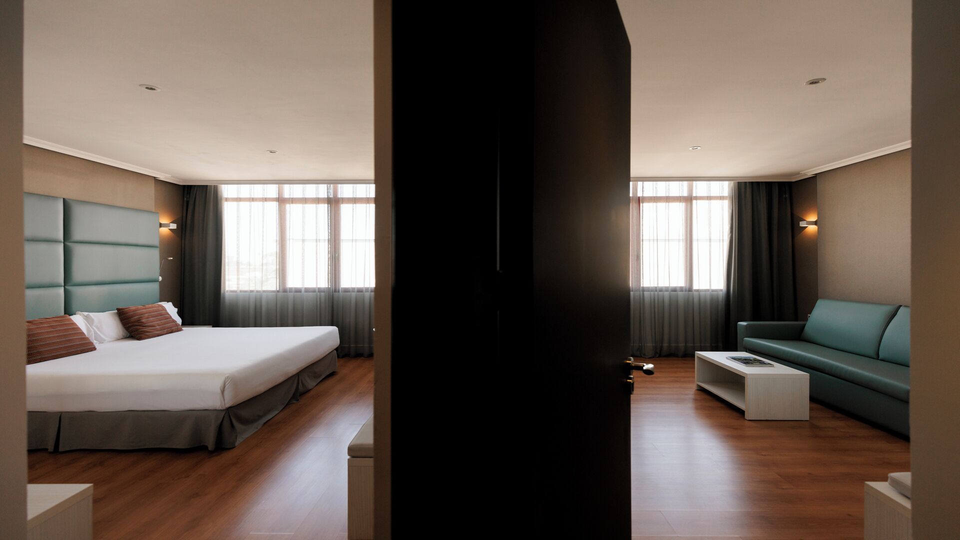 A modern hotel room with a large bed, a sofa, and a coffee table.