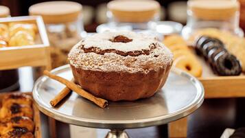 A cake on a metal stand with a cinnamon stick beside it.