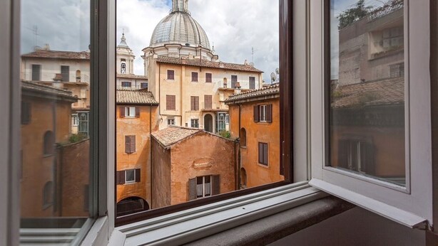 Une vue à travers une fenêtre d’un bâtiment doté d’un dôme et de structures adjacentes.