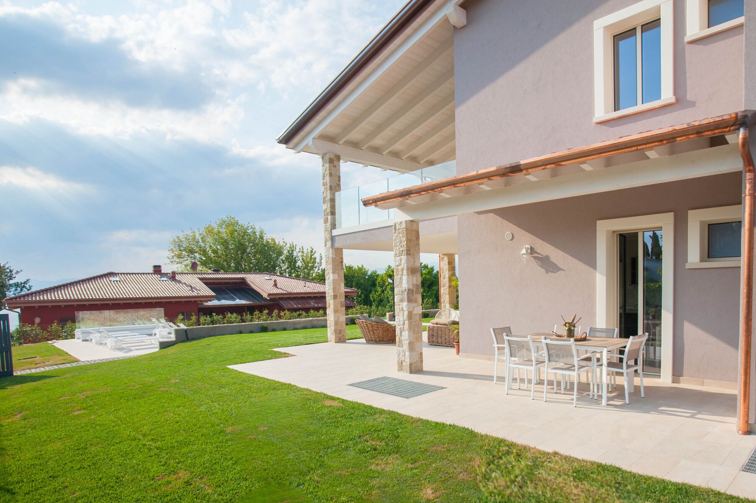 A modern house with a covered patio, a lawn, and a neighboring building.