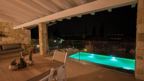 Patio esterno con piscina, muri in pietra e ringhiera in vetro.